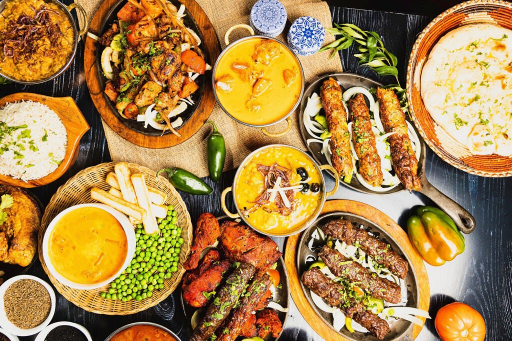 Overhead restaurant food photography flat lay of Indian and Pakistani dishes on a dark wooden table