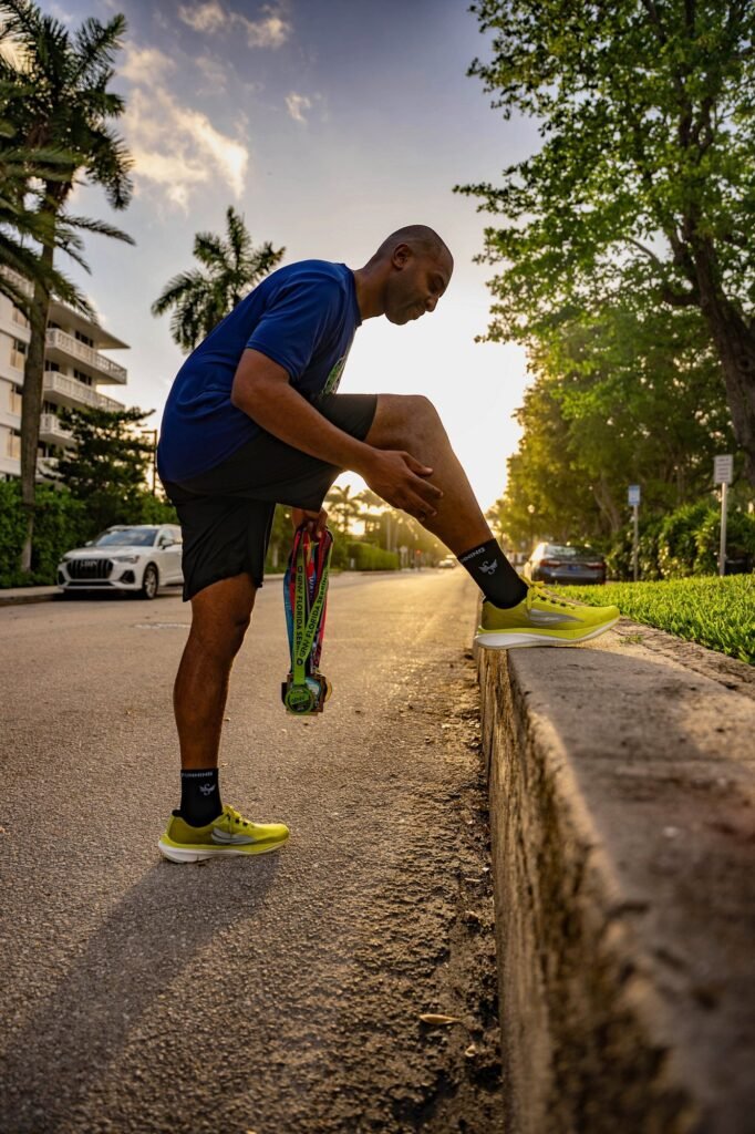 Runner stretching on a curb at golden hour on a palm-lined street for a running brand lifestyle shoot
