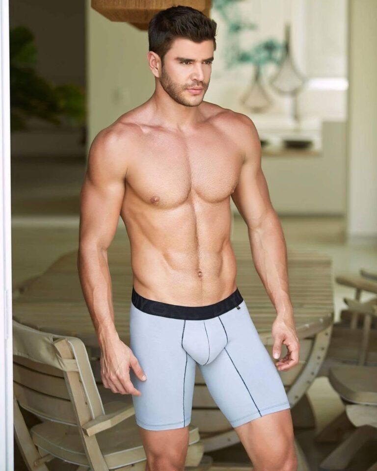 Male model in boxer briefs standing by a sunlit window, men's underwear brand campaign