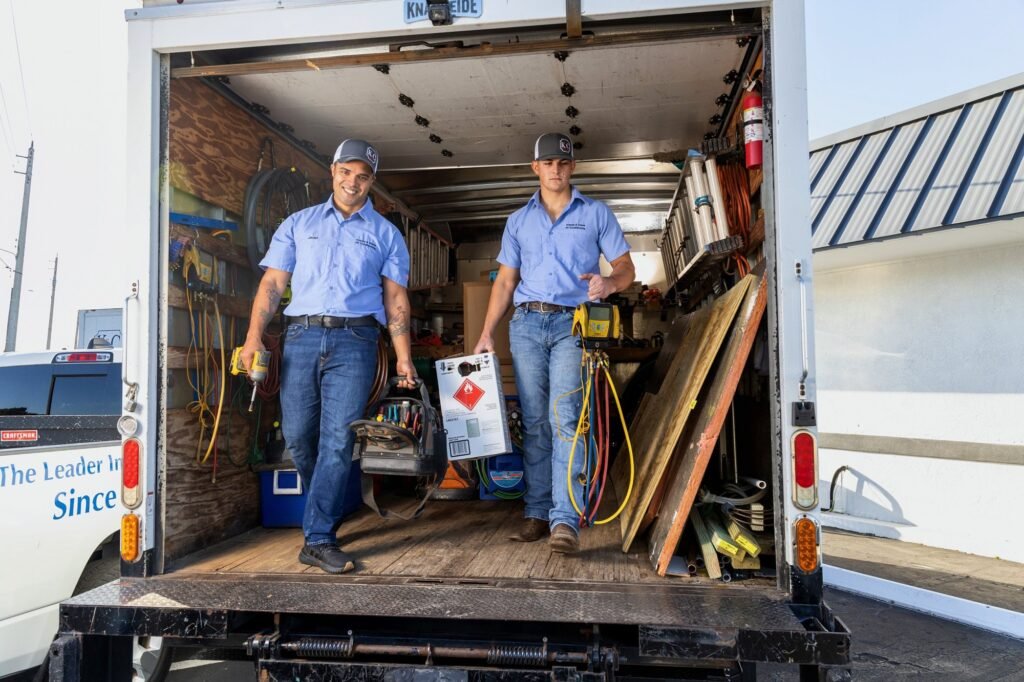 Brand photography of two HVAC technicians unloading equipment from a branded work truck