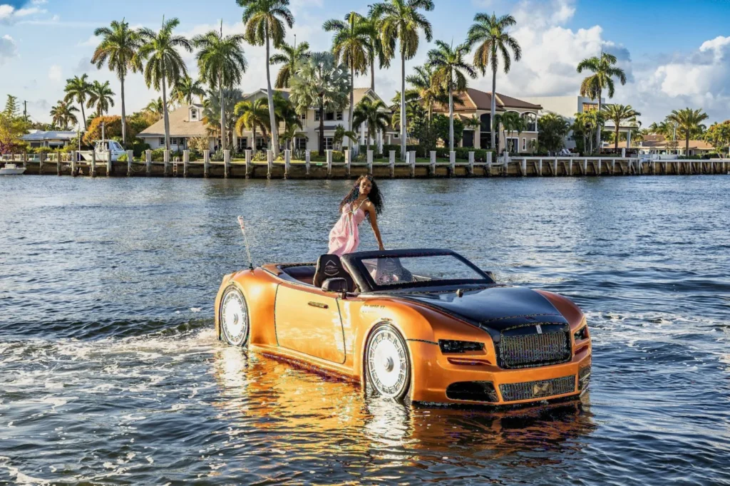 Editorial photoshoot of a woman in a pink dress riding an amphibious convertible car on the water in South Florida