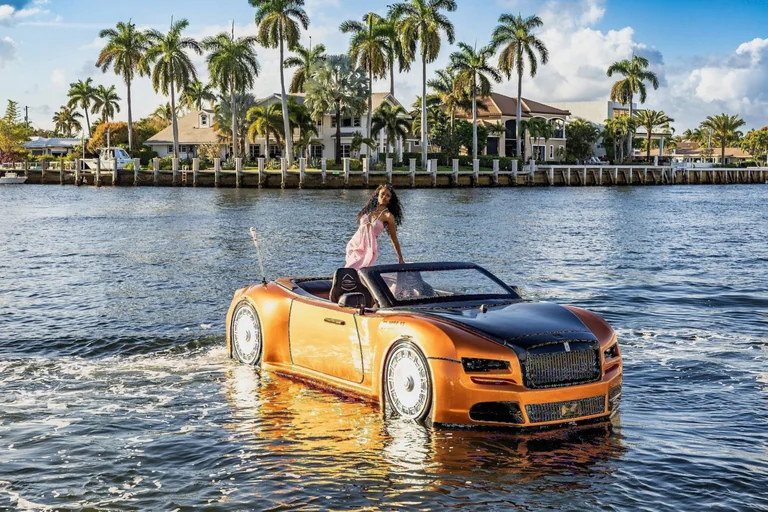 Editorial photoshoot of a woman in a pink dress riding an amphibious convertible car on the water in South Florida